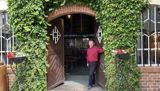 Der Hausherr im bl&uuml;henden Innenhof vor der rustikalen Niederlage (Foto: oas)