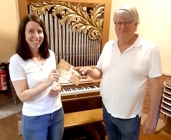 Kantorin Laura Schildmann und Orgelbauer Sicco Steendam bei der &Uuml;bergabe der Festschrift an der Kleinen Strobelorgel" (Foto: Stadtverwaltung Bad Frankenhausen)
