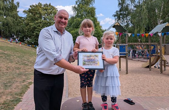 Marlen und Magdalena &uuml;berreichten B&uuml;rgermeister Steffen Grimm ein Andenken zum 50. Geburtstag der Kita Pusteblume. (Foto: Janine Skara)