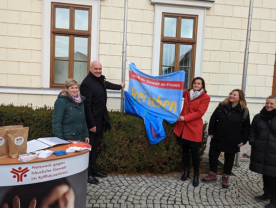 andr&auml;tin Antje Hochwind-Schneider (3.v.re.) und B&uuml;rgermeister Steffen Grimm (2.v.li.) hissen beim Aktionstag gegen h&auml;usliche Gewalt die Flagge als Symbol f&uuml;r die gemeinsame Zusammenarbeit gegen Gewalt an Frauen und M&auml;dchen im Kyffh&auml;userkreis. (Foto: Janne Skara)