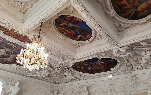Bild: Kronleuchter (Mitte) und dezente Sicherheitsbeleuchtung am Wandgesims im Riesensaal von Schloss Sonderhausen