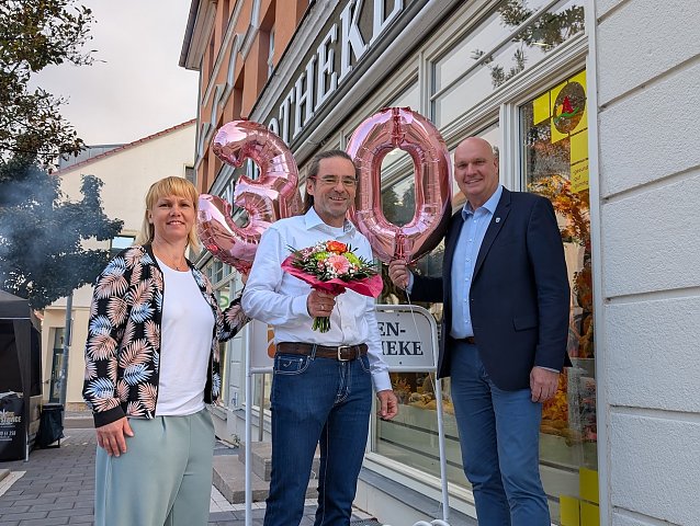 Bild: Citymanagerin Kathrin Kilian (li.) und B&uuml;rgermeister Steffen Grimm (re.) gratulierten Thomas Wi&szlig;gott zum 30. Geburtstag der Loewen-Apotheke.