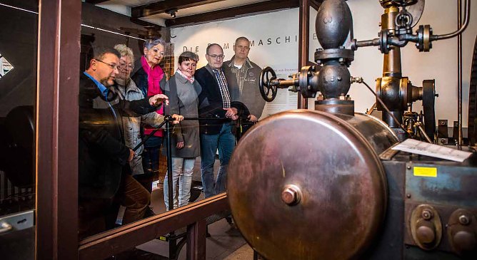 Thomas M&uuml;ller (links) erkl&auml;rt seinen G&auml;sten die Funktionsweise einer Dampfmaschine (Foto: Traditionsbrennerei)