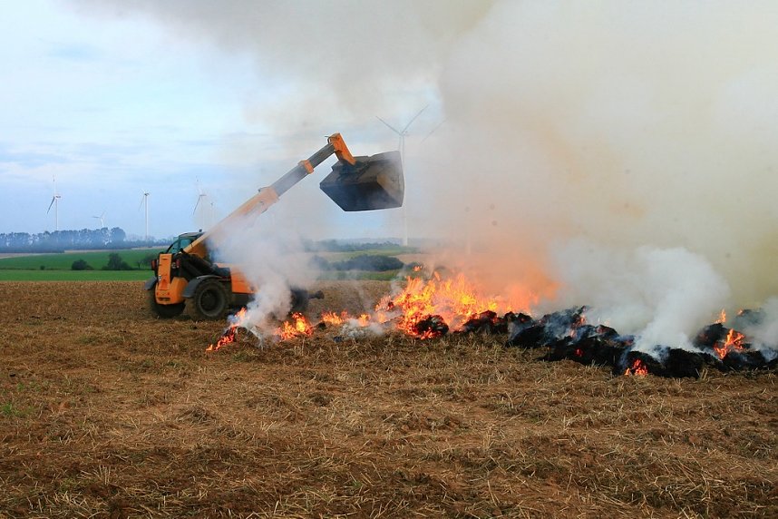Brennende Strohballen zwischen Holz- und Kirchengel